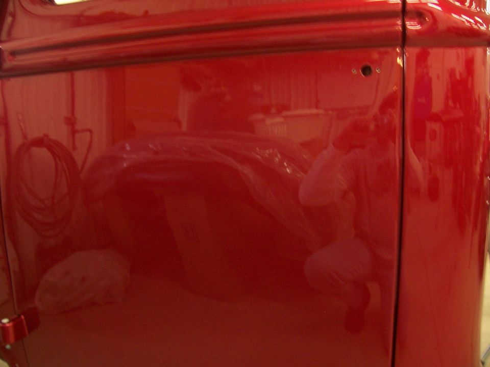 reflection of person on shiny red vehicle door