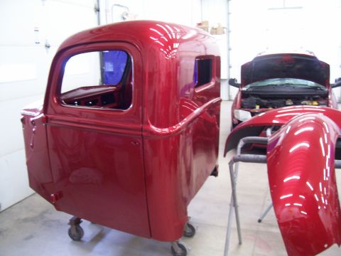1978 Ford F-150 - A red truck cab is in the foreground, with a red minivan and car parts in the background.