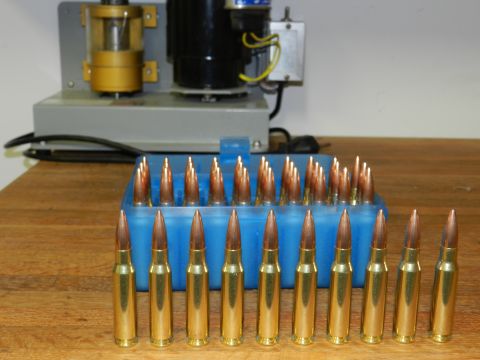 1996 Ford Bronco - A collection of rifle cartridges is displayed next to reloading equipment on a wooden surface.