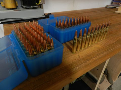 1996 Ford Bronco - Two blue plastic ammunition boxes filled with cartridges sit on a wooden table, with loose cartridges lined up to the right.