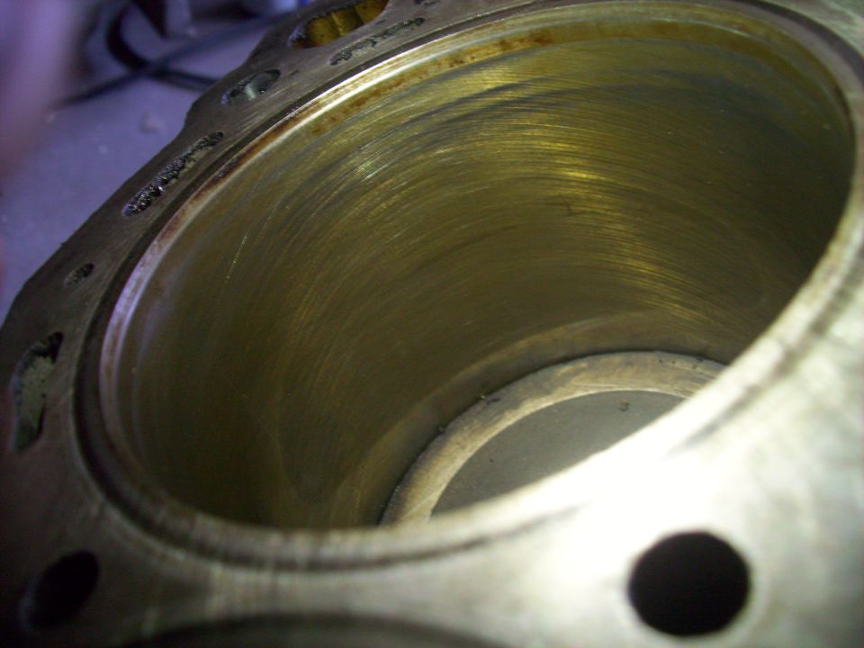 Close-up looking into a polished engine cylinder bore with the piston at the bottom