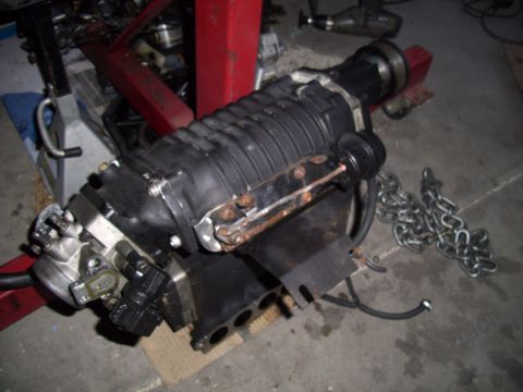 2003 Hyundai Tiburon - A supercharger assembly, likely for an engine, is shown with a throttle body and a length of chain.