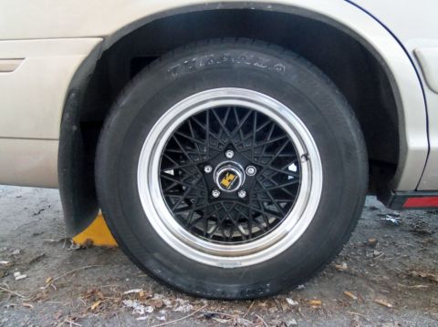 2000 Mercury Grand Marquis - Close-up of a car's wheel and tire, showing a black mesh design with a chrome lip.