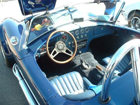 1995 Ford Crown Victoria - The interior of a blue convertible sports car features a wood-rimmed steering wheel and a dashboard filled with gauges.
