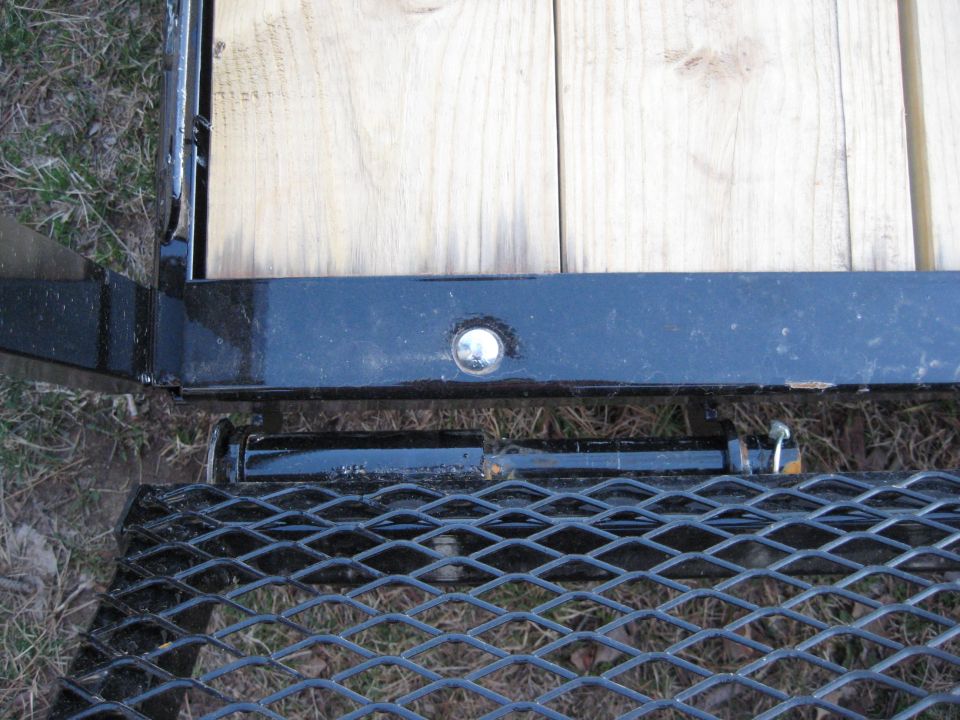 Close-up of a trailer ramp latch mechanism and wooden deck