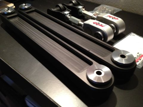 1992 Ford Crown Victoria - Aftermarket control arms with adjustable end links and red logos are laid out on a dark surface.
