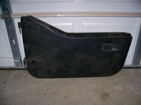 2000 Jeep Wrangler - A single black Jeep door is shown, detached from the vehicle, resting on a garage floor.