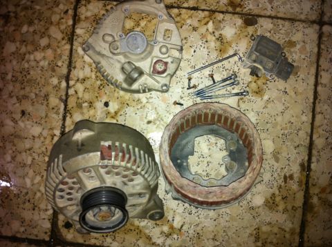 1998 Ford Crown Victoria - Components of a disassembled alternator, including the rotor, stator, and voltage regulator, are laid out with tools and fasteners.
