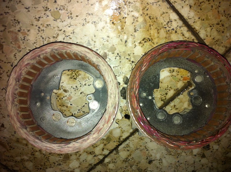 Two electric motor stators with copper windings on a speckled floor.