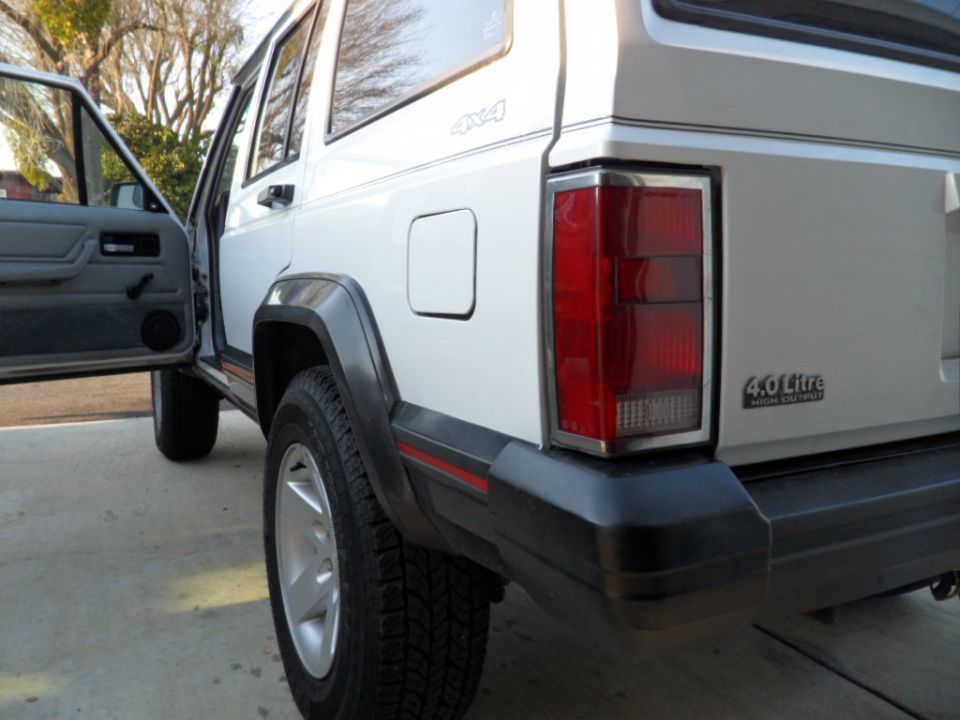 White 1994 Jeep Cherokee rear passenger side view with open door.
