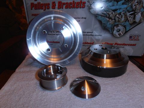 1990 Ford Bronco - A set of aluminum pulleys and brackets are displayed on a towel, with a box depicting an engine in the background.