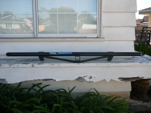 1988 Ford Bronco - Black metal bar with blue sticker, mounted on a white ledge with plants below.
