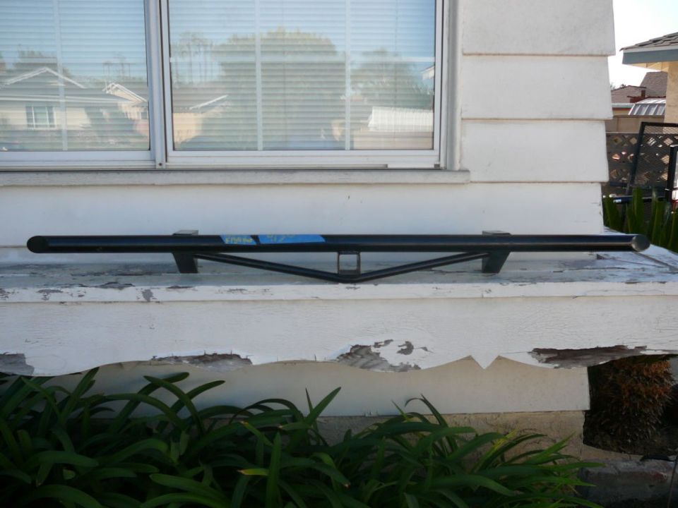 Black metal bar with blue sticker, mounted on white ledge