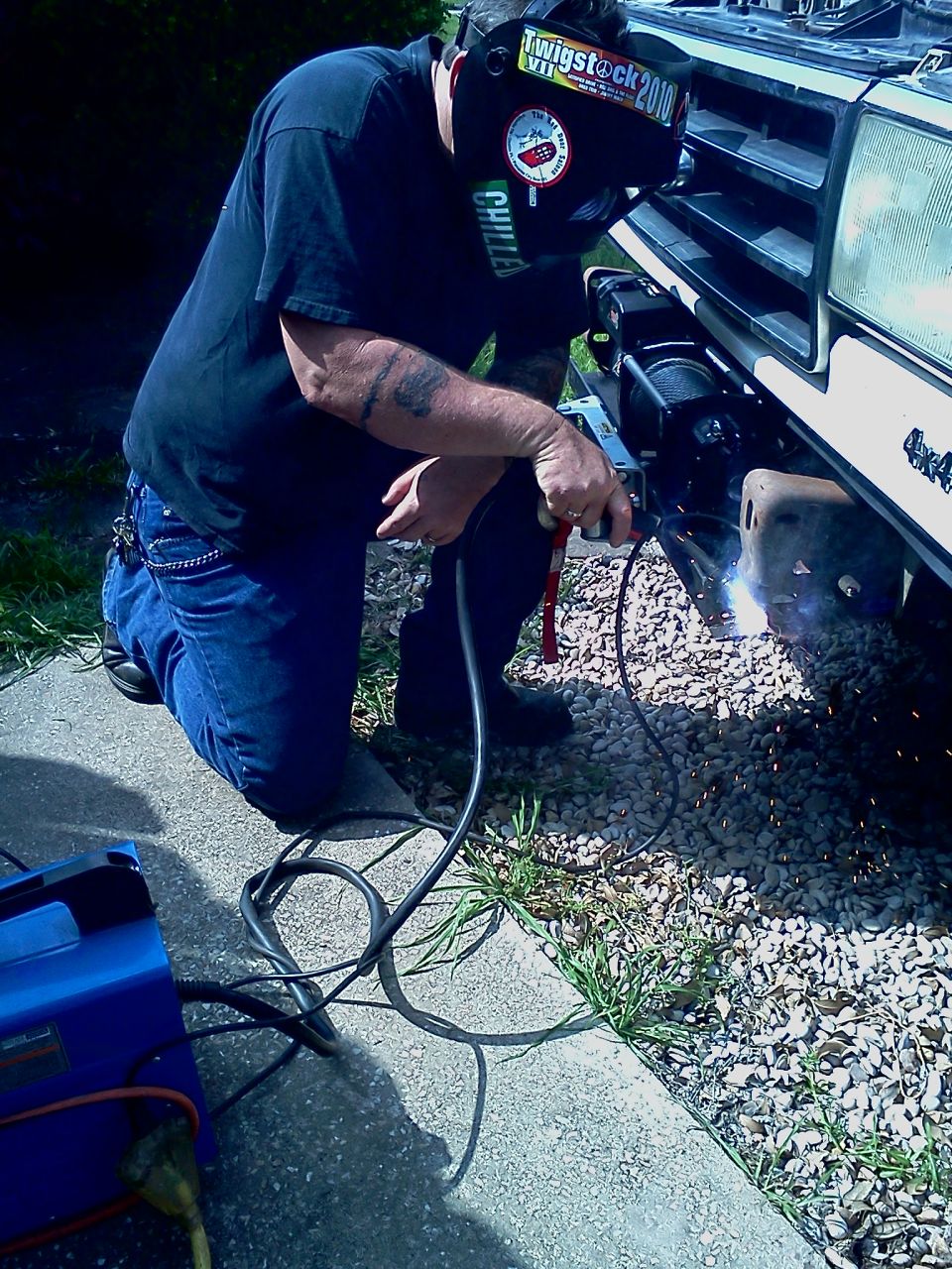 Man welding a winch mount on the front of a 1989 Ford Bronco