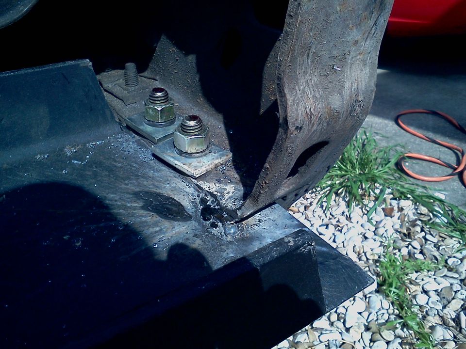 Bolts and nuts securing a metal bracket to a larger metal component, possibly part of a winch mount