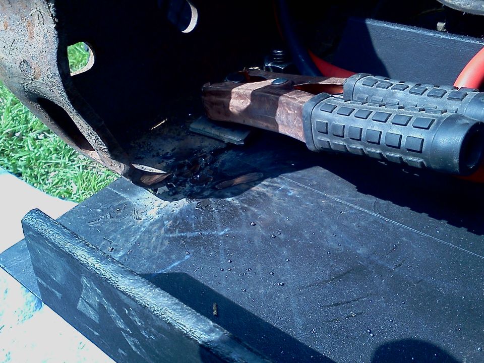 Winch mount with rusty metal and black rubber grips, on a dark surface