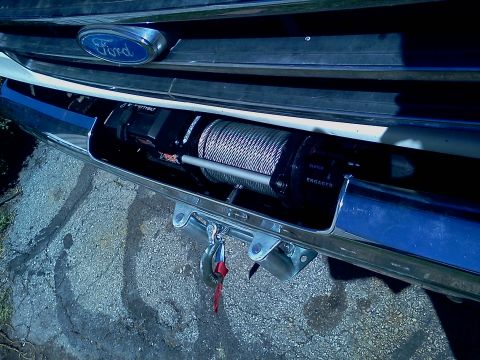 1989 Ford Bronco - A winch is mounted in the front bumper of a Ford truck, with the Ford logo visible on the grille.