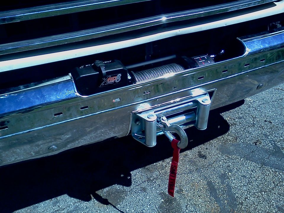 Chrome bumper with a winch and red strap attached to a hook