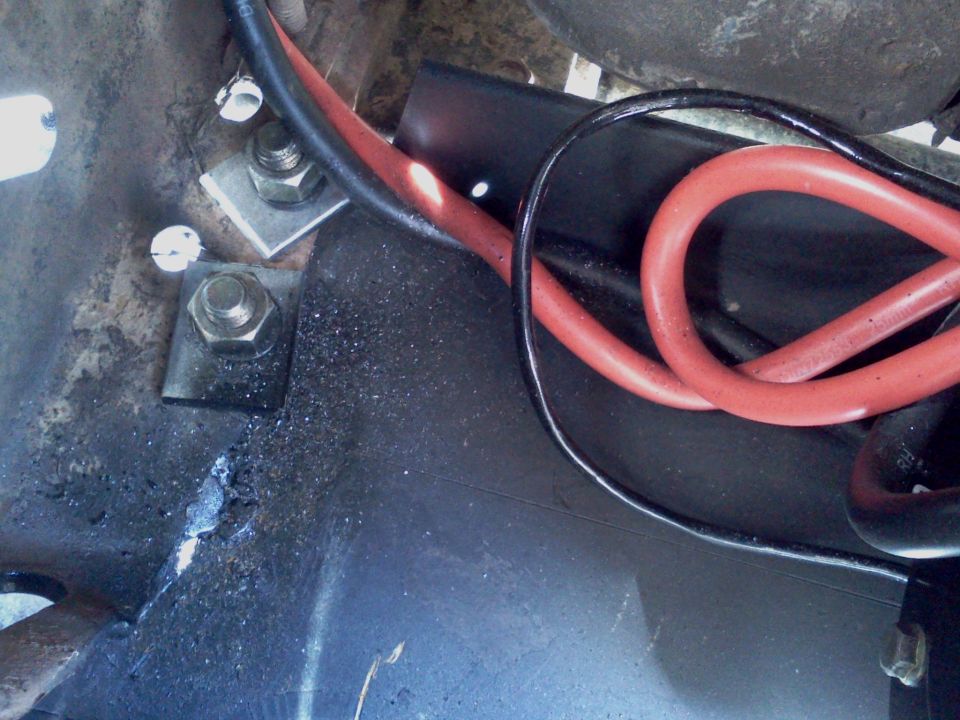 Close-up of red and black battery cables connected to mounting hardware with bolts