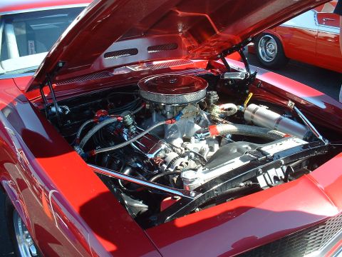 1995 Ford Crown Victoria - Engine bay of a red car with the hood open, showing a V8 engine and chrome accents.