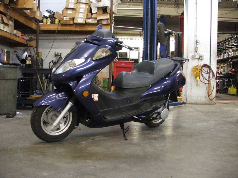 Dark blue scooter side view with a sticker showing '213'