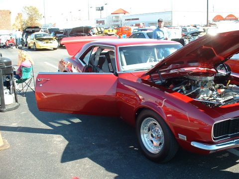 1995 Ford Crown Victoria - A red 1969 Chevrolet Camaro is displayed with its hood open, showing the engine.