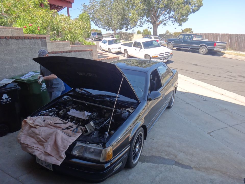 1993 Ford Taurus with hood open, showing engine. Other vehicles visible in background