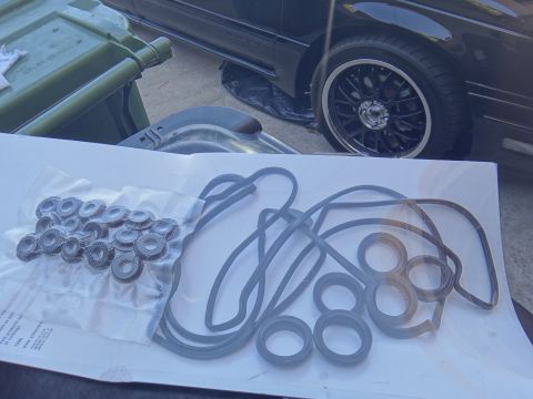 1993 Ford Taurus - A collection of engine gaskets and seals are displayed on a white surface, with a car's wheel and a green bin visible behind.