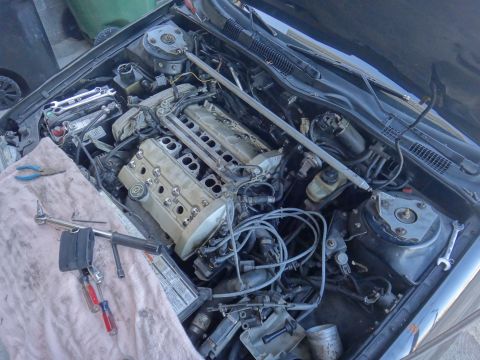 1993 Ford Taurus - The engine bay of a 1993 Ford Taurus, with various tools laid out on a cloth.