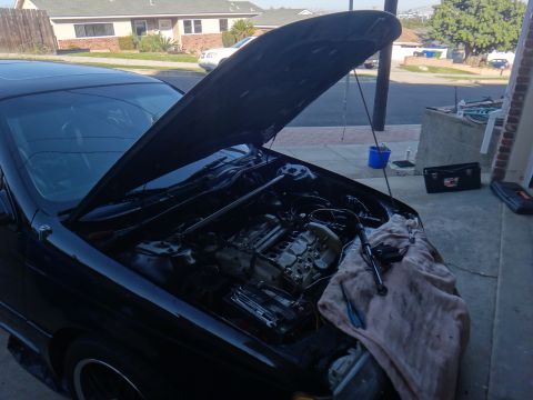 1993 Ford Taurus - Engine bay of a black car with the hood open, revealing a partially disassembled engine and tools.