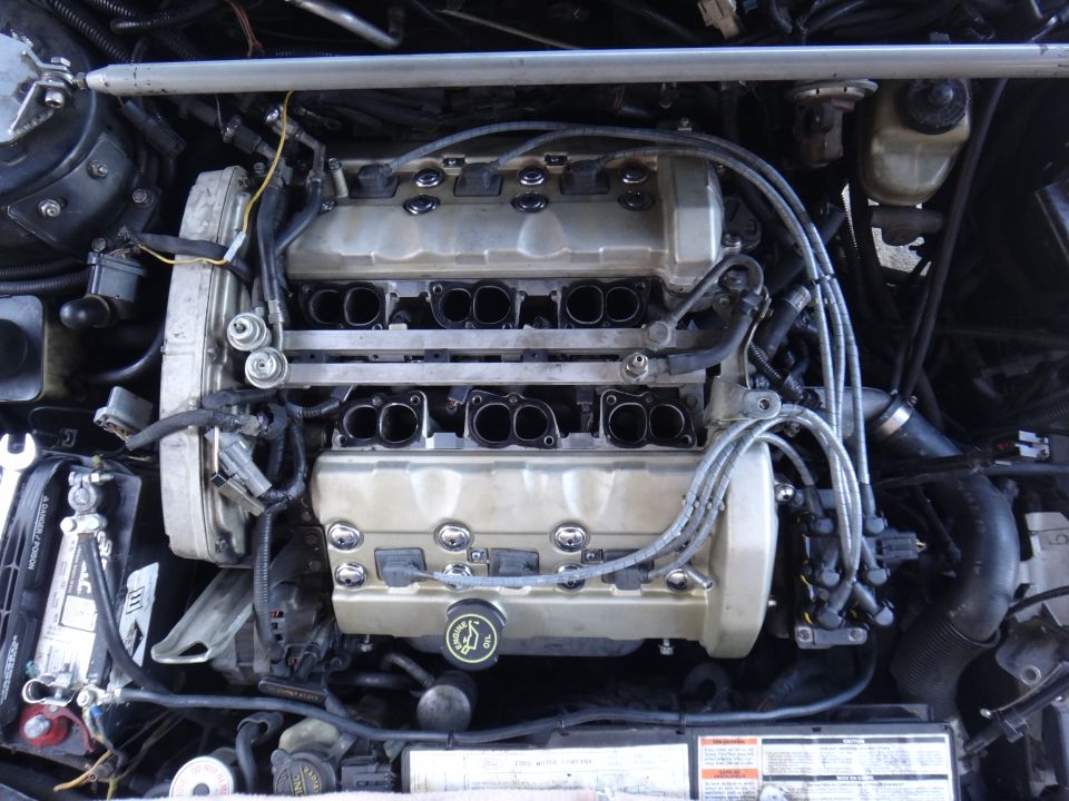 Engine bay with V-engine, intake manifold removed, and spark plug wires visible