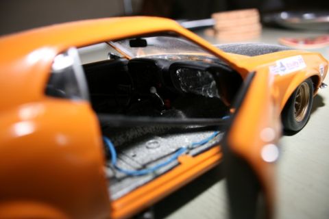 1970 Ford Mustang - Interior view of an orange 1970 Ford Mustang diecast model, visible wiring and interior components.
