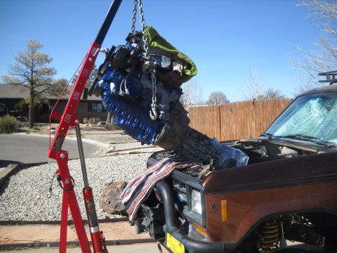 1992 Ford Explorer - An engine is hoisted out of a brown SUV during a repair or replacement.