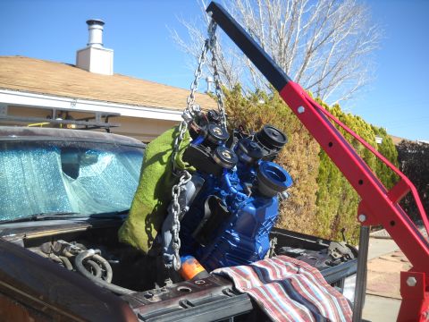1992 Ford Explorer - An engine is being removed from a vehicle using an engine hoist, with a house and trees in the background.