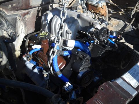 1992 Ford Explorer - Engine assembly with blue hoses and chains, likely being removed or installed.