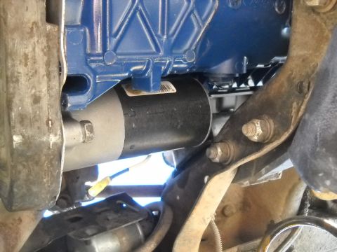 1992 Ford Explorer - Close-up view of a starter motor attached to a blue engine block, with visible mounting hardware and wiring.