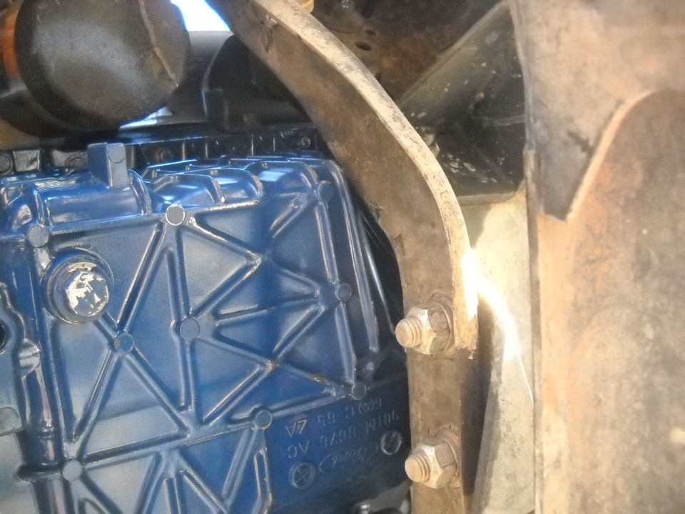 Close-up of a blue engine component with visible part numbers and mounting bolts