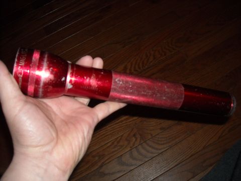 1979 Ford F-150 - A red Maglite flashlight is held in a person's hand against a wooden floor background.