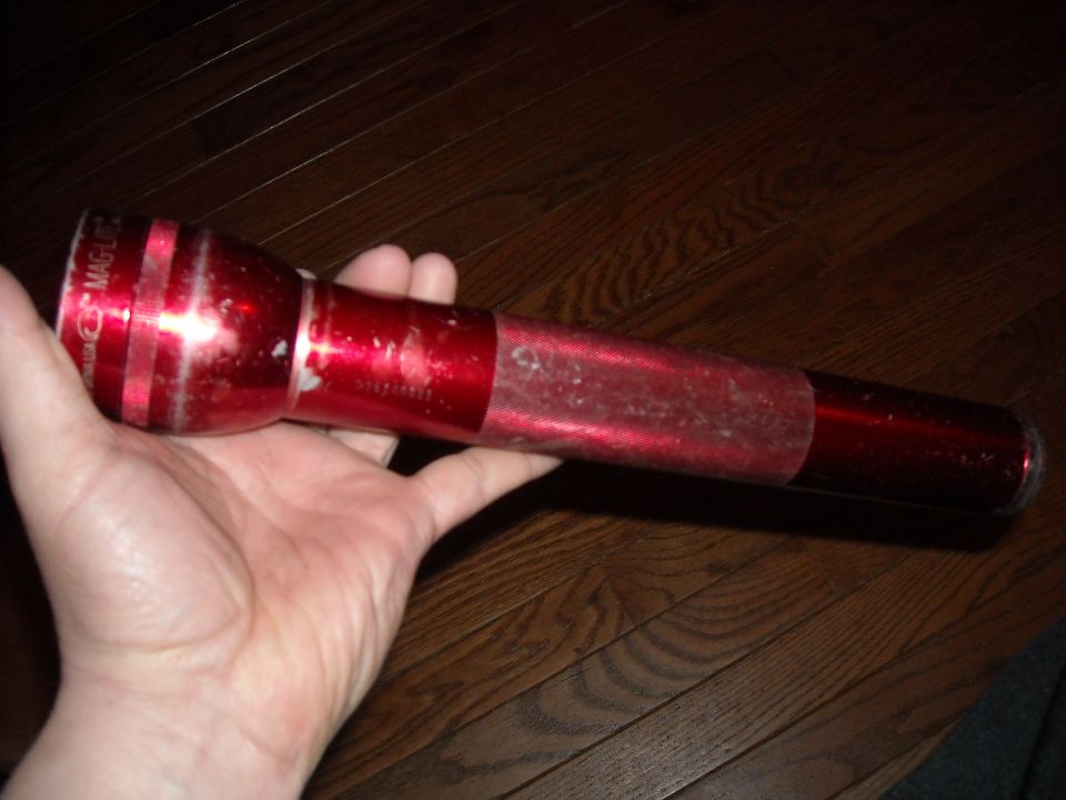 Red Maglite flashlight held in a hand