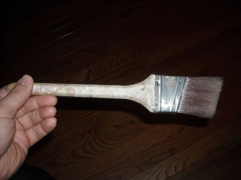 1979 Ford F-150 - A paint brush is held in a hand against a dark wood background.