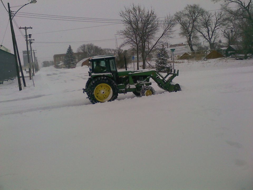 Tractor with front loader plowing snow on a street