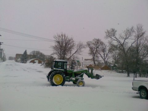 1966 Ford Bronco - A green tractor with a front loader is parked in a snowy landscape, with a white pickup truck visible on the right.