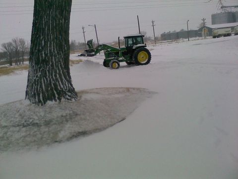 1966 Ford Bronco - A tractor with a front loader is parked in a snowy field near a large tree.