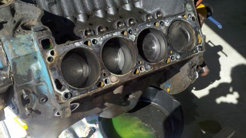 1978 Ford Bronco - Engine block with four cylinders visible, some blue paint, and a drain pan with green fluid.