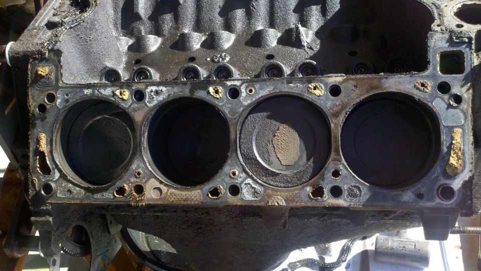 Engine block with four cylinders visible, showing wear and some debris