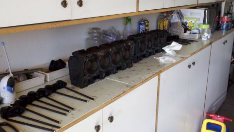 1978 Ford Bronco - Engine parts, including cylinder heads and pushrods, are laid out on a workbench for a rebuild or rebuild project.