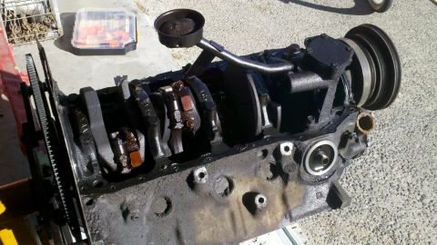 1978 Ford Bronco - Disassembled engine block with internal components visible, resting on a concrete surface.