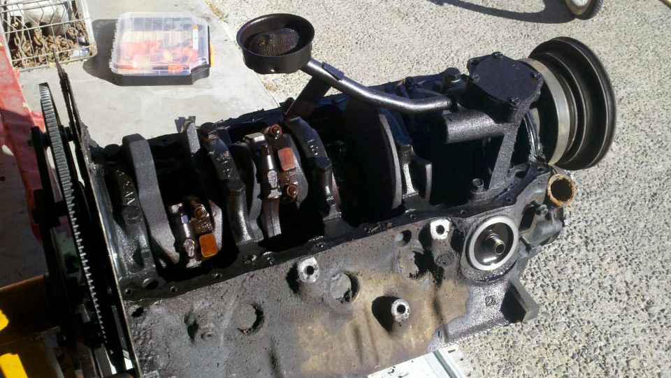 Engine block with crankshaft, connecting rods, oil pump pickup tube, and pulley. Dirty, disassembled