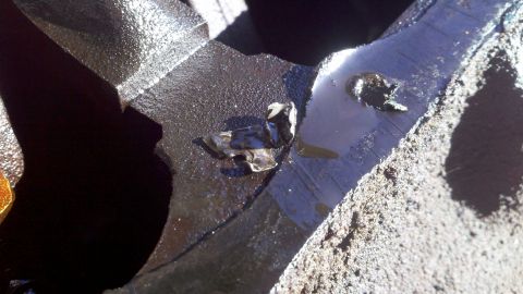 1978 Ford Bronco - A close-up view of a damaged engine component, showing debris and oil residue.