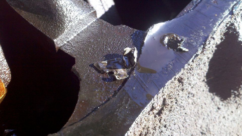 Close-up of a damaged engine part with debris and oil